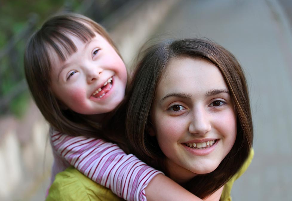 Older girl giving younger girl a piggyback