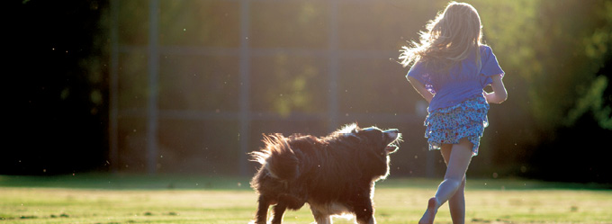 Girl running with her dog on the oval